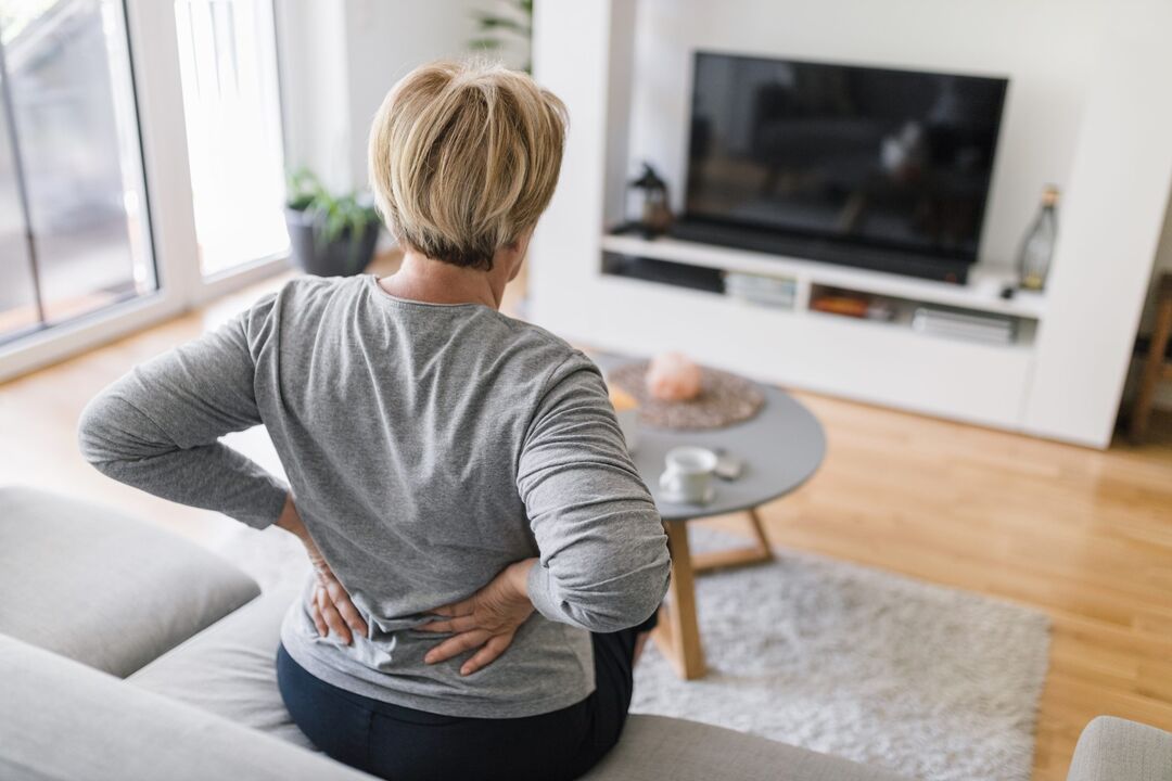 Eine Frau macht sich Sorgen über Rückenschmerzen im Lendenbereich. 